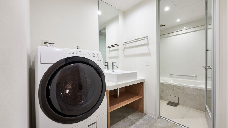 レジデンシャルツインルームのバスルームと洗濯乾燥機。長期滞在に便利です。