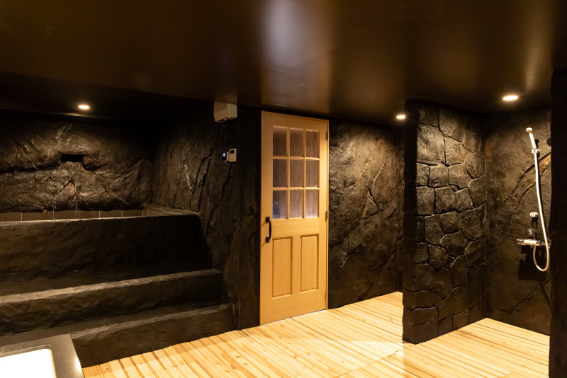岩に囲まれた、異空間でととのう。 無骨な岩壁、温かみのある木の床。